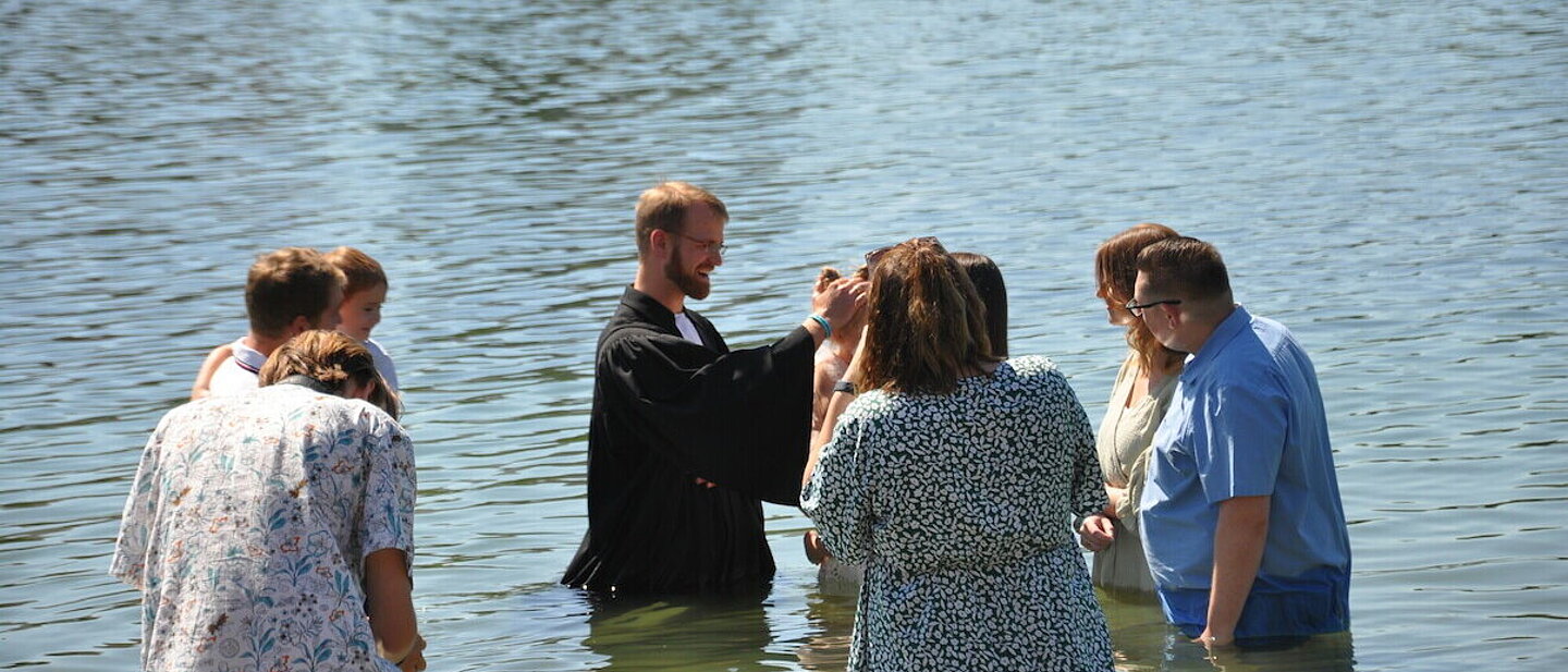 Ein Mädchen wird von Pfarrer Lukas von Nordheim beim Bensheim Tauffest 2022 im Badesee getauft.